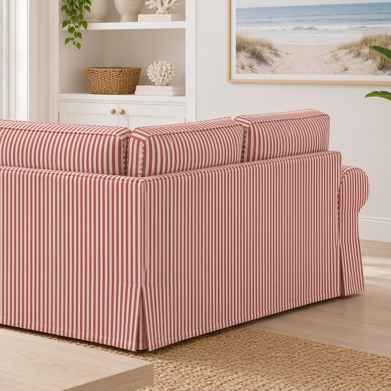 A terracotta vertically striped slipcovered sofa in a bright, modern living room with a beach view window and potted plants.