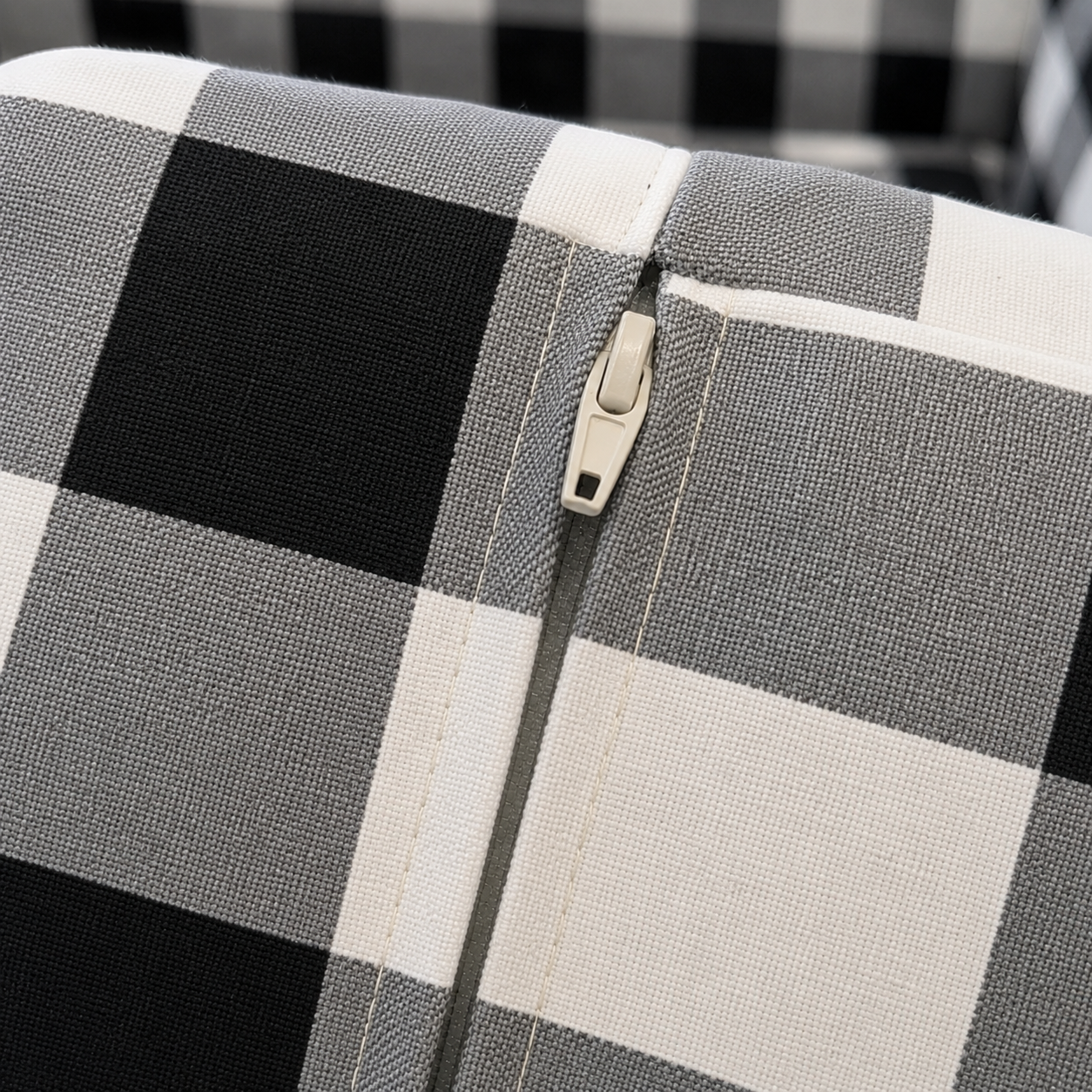Close-up of a checkered fabric with a zipper detail on a black and white checkered background.