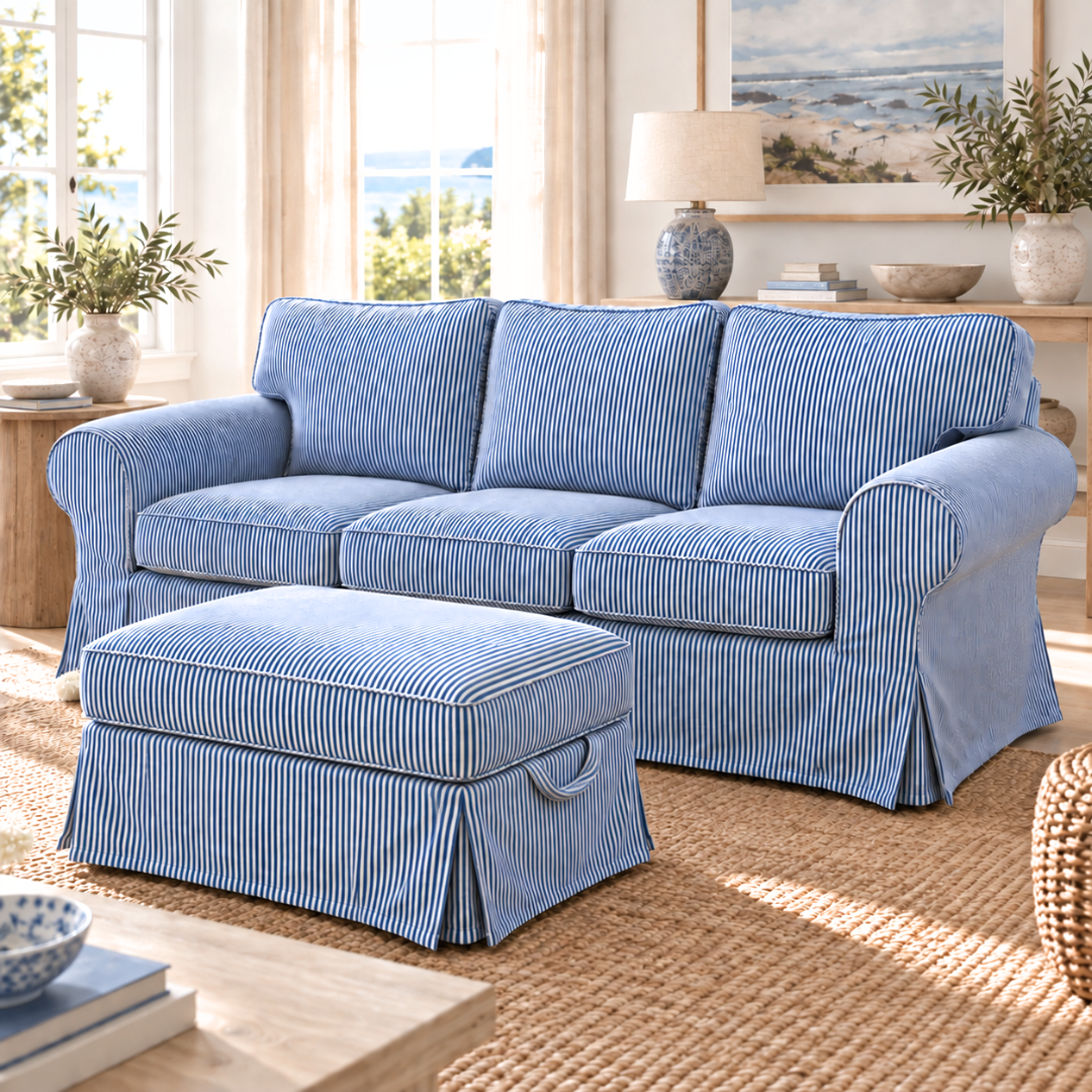 A blue and white striped slipcovered sofa with matching ottoman in a bright, sunlit living room.