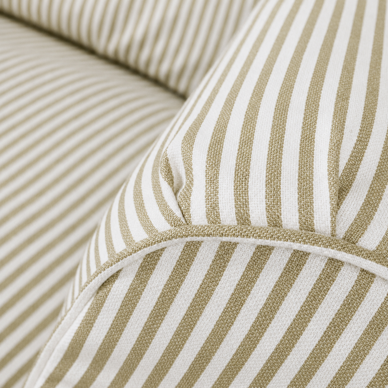 Close-up of striped fabric upholstery in warm beige and off-white, showing the woven texture and curved seam detail.