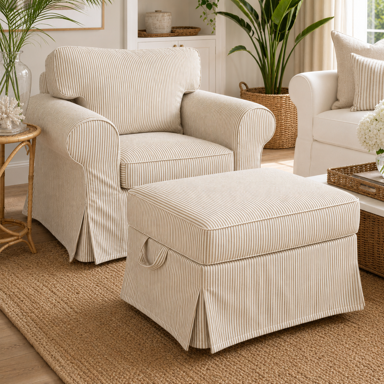 A cream-colored slipcovered armchair with a matching ottoman in a bright, styled living room setting.