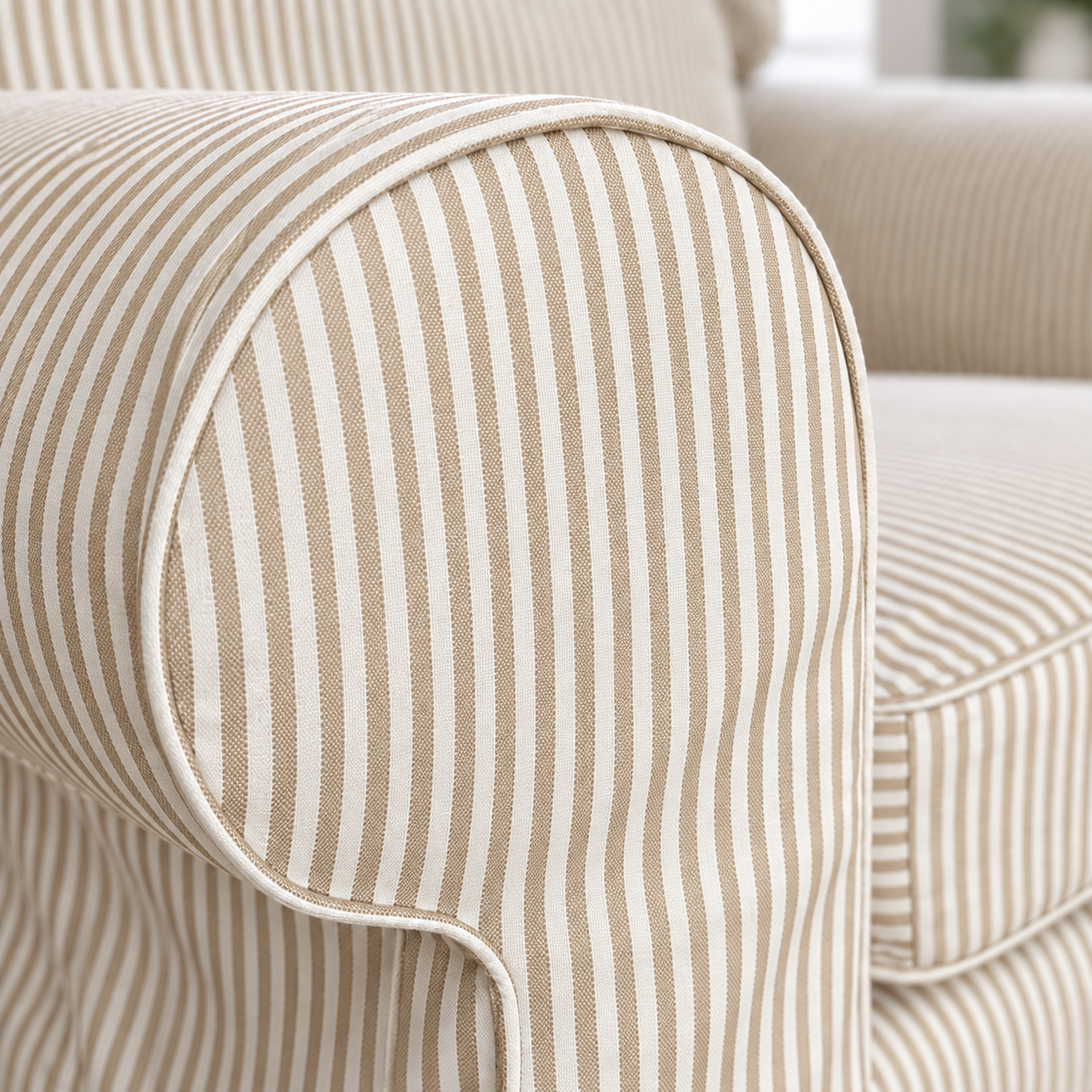 Close-up of a striped upholstered armrest with beige and off-white vertical stripes and clean piping.