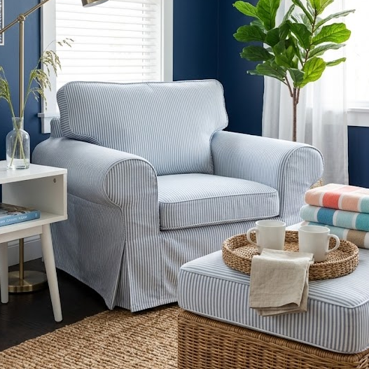 Living room with blue walls, a gray armchair, and a wicker ottoman.