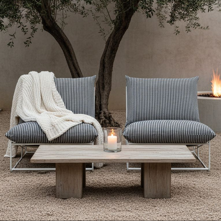 Outdoor seating area with two chairs and a table under a tree, featuring a fire pit in the background.