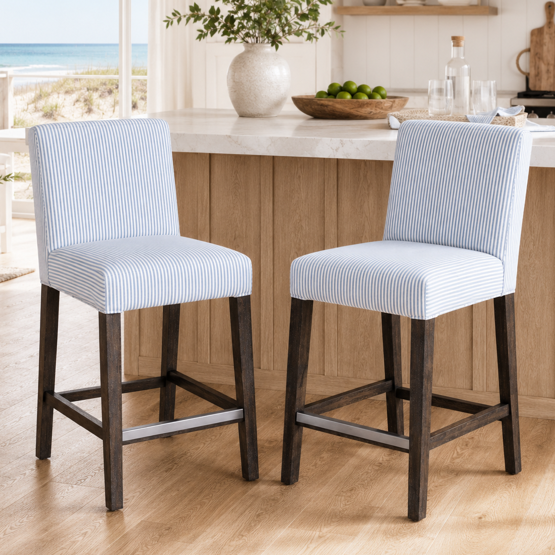 Two blue cushioned bar stools in a kitchen with a view of the ocean.