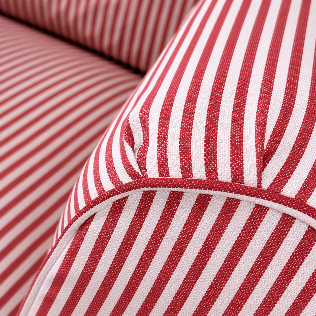 Close-up of red and white striped fabric upholstery, showing the texture and pattern of a cushion or sofa arm.