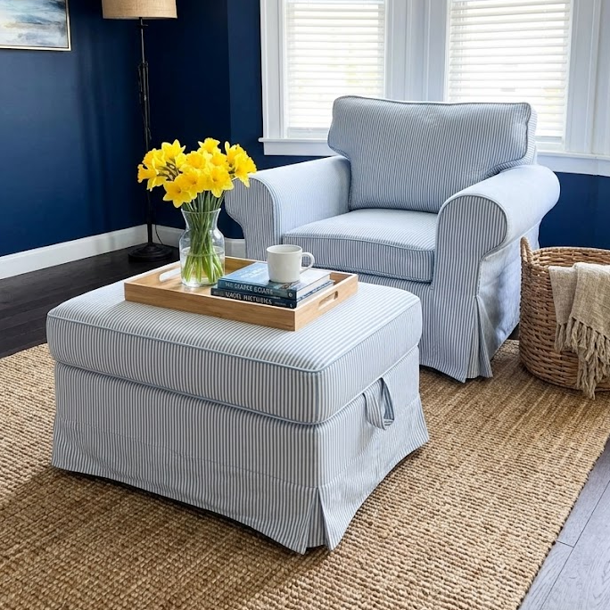 Living room with blue walls, gray armchair, ottoman, and yellow flowers.