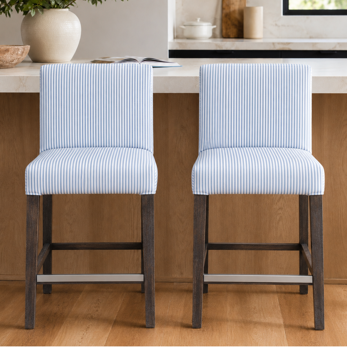 Two blue striped bar stools in a kitchen setting with wooden flooring and a countertop.