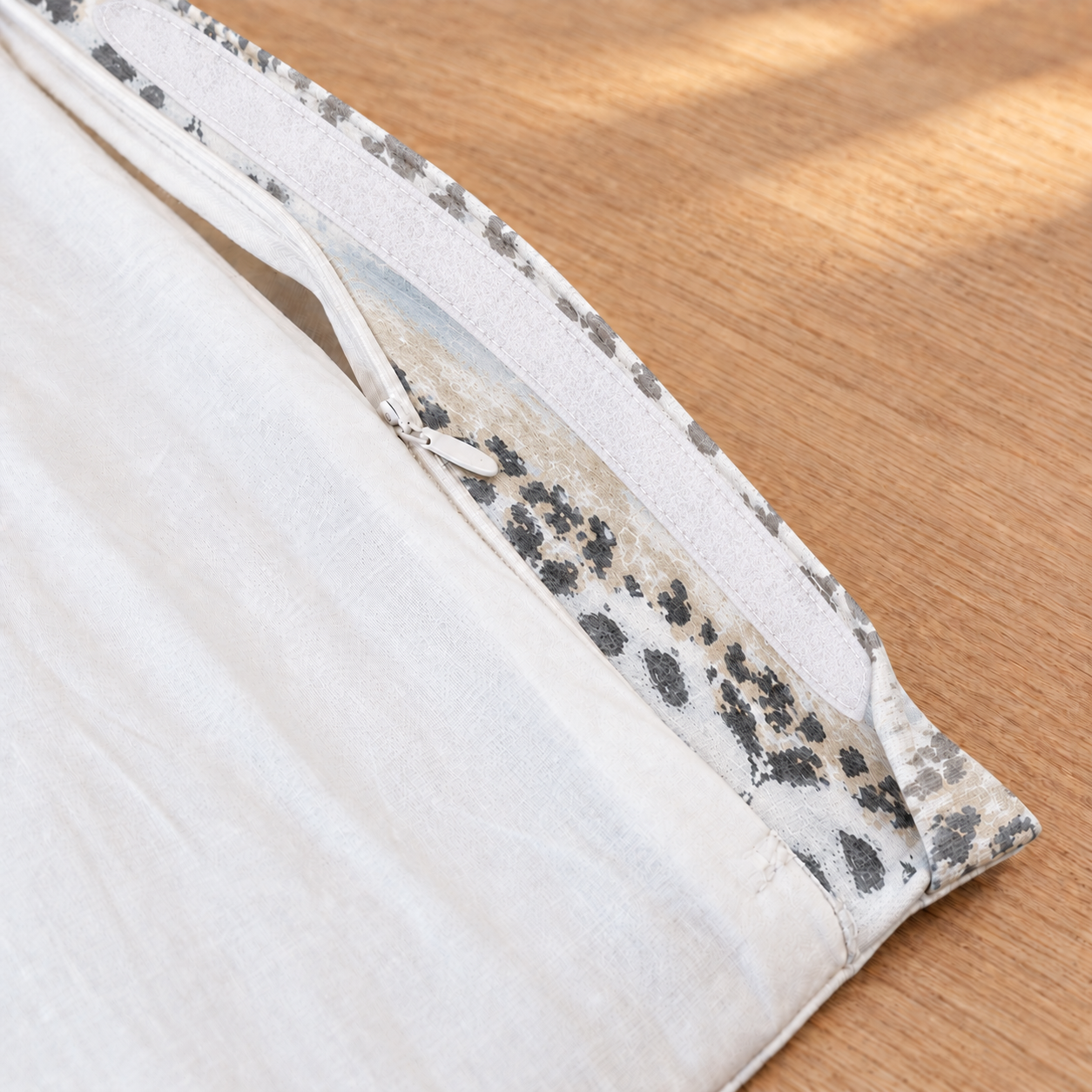 Close-up of an IKEA Kids Poang cushion cover folded over on a light wood surface with a gray and white speckled patterned edge.