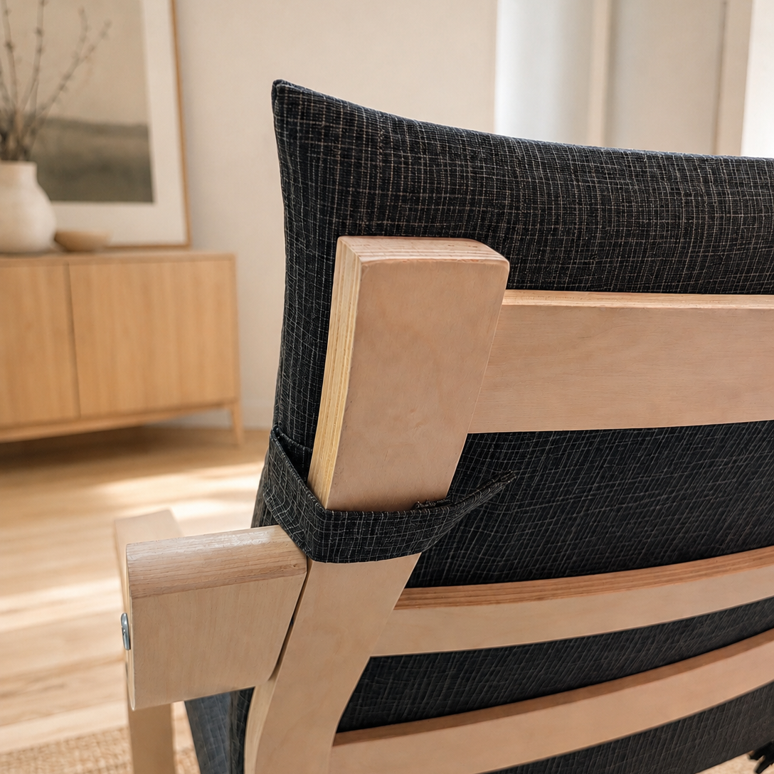Close-up of a modern wooden chair with a dark charcoal textured fabric sling seat and natural light wood frame, shown in a bright, modern room setting.