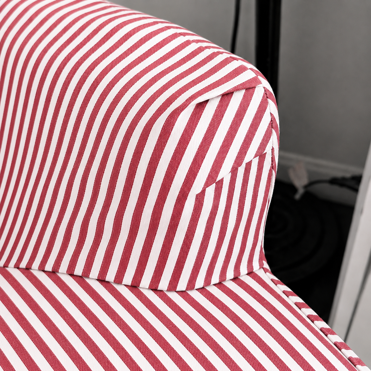 Close-up of a red and white vertically striped fabric sofa slipcover, showing the armrest and seat cushion detail.