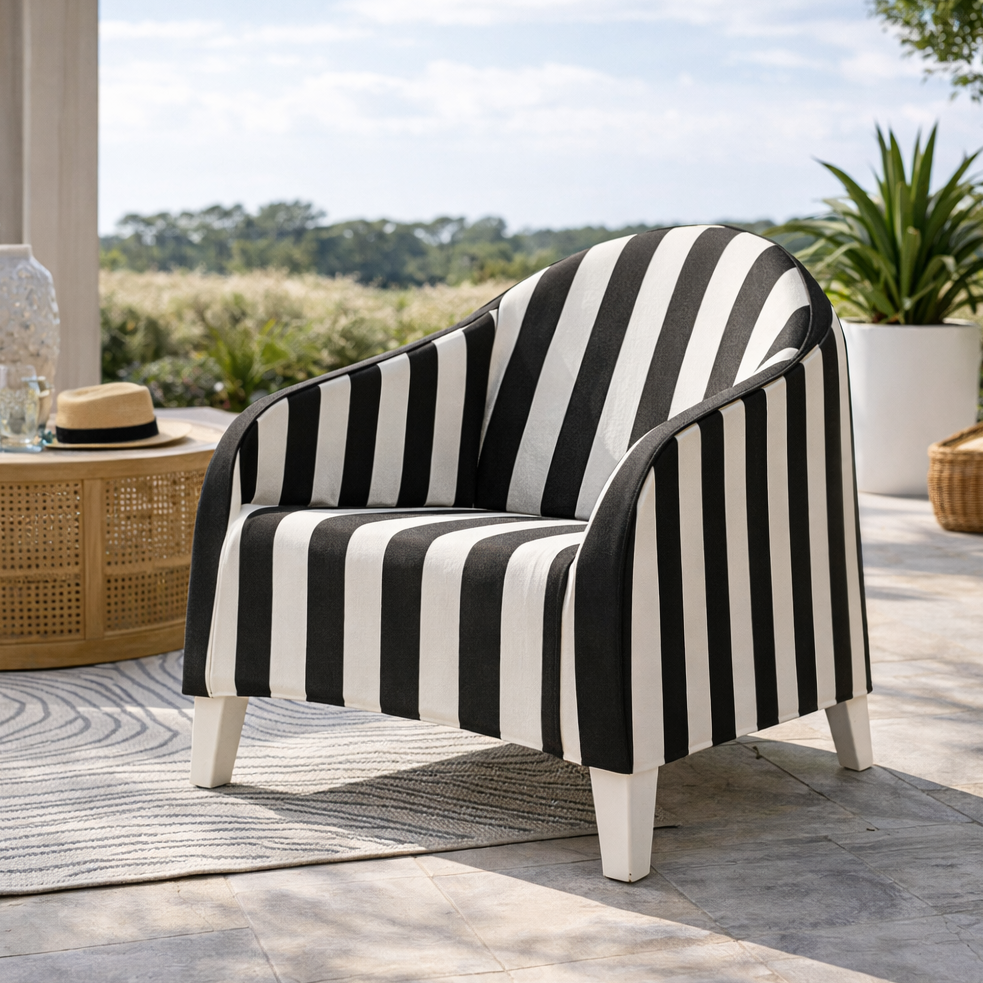 Black and white striped armchair on a patio with outdoor furniture and plants.