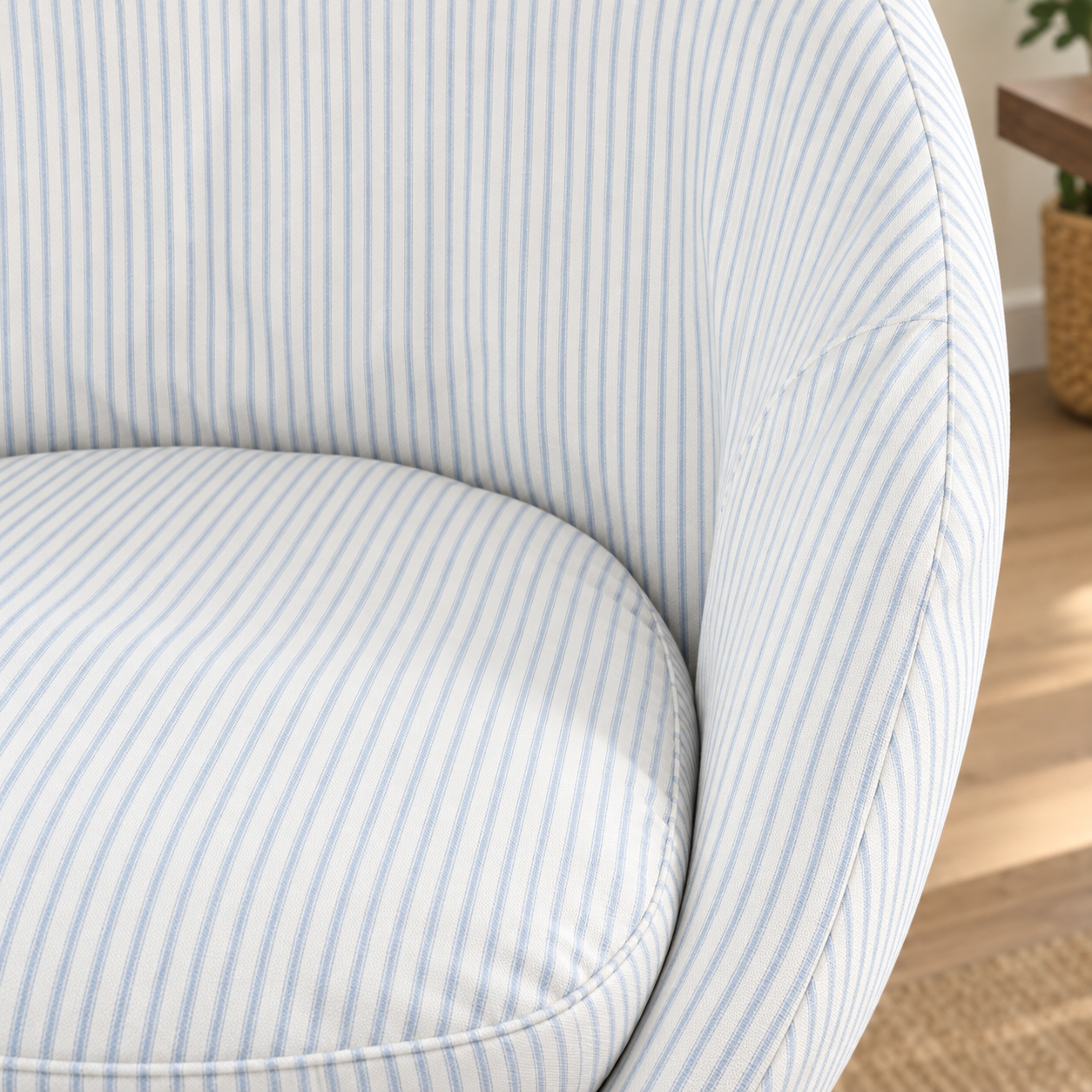 Close-up of a curved upholstered chair with light blue and white vertical pinstripes, showing the seat cushion and backrest in a softly lit interior setting.