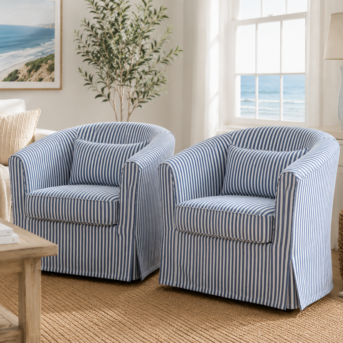 Two matching slipcovered armchairs with blue and white vertical stripes, styled in a bright, coastal-themed living room.