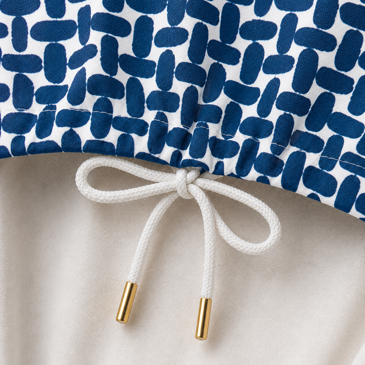 White shoelace with gold ends on a white background with blue geometric pattern