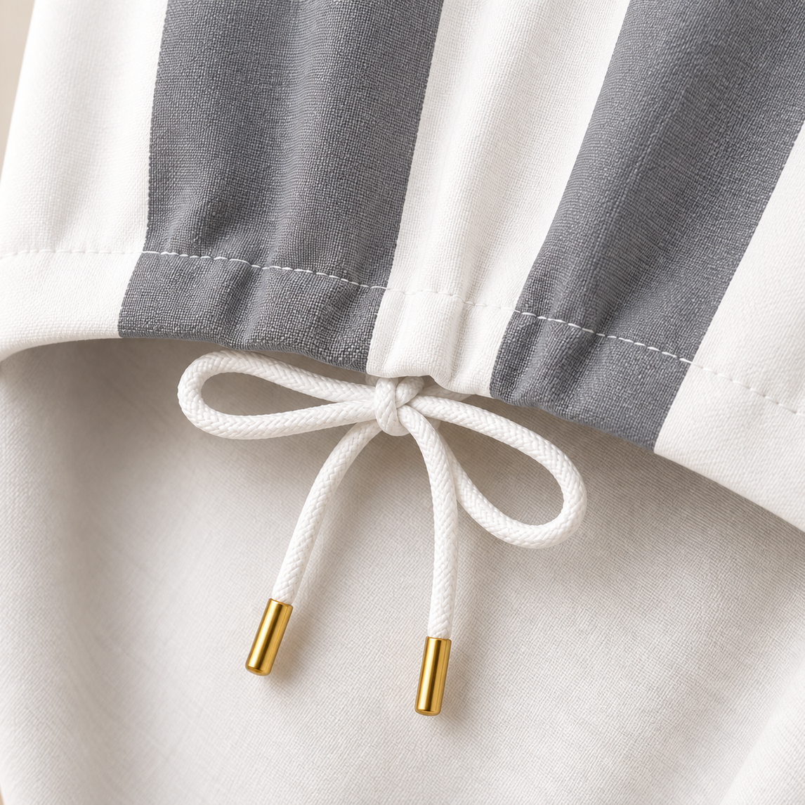 Close-up of grey and white striped cover drawstring with gold tips