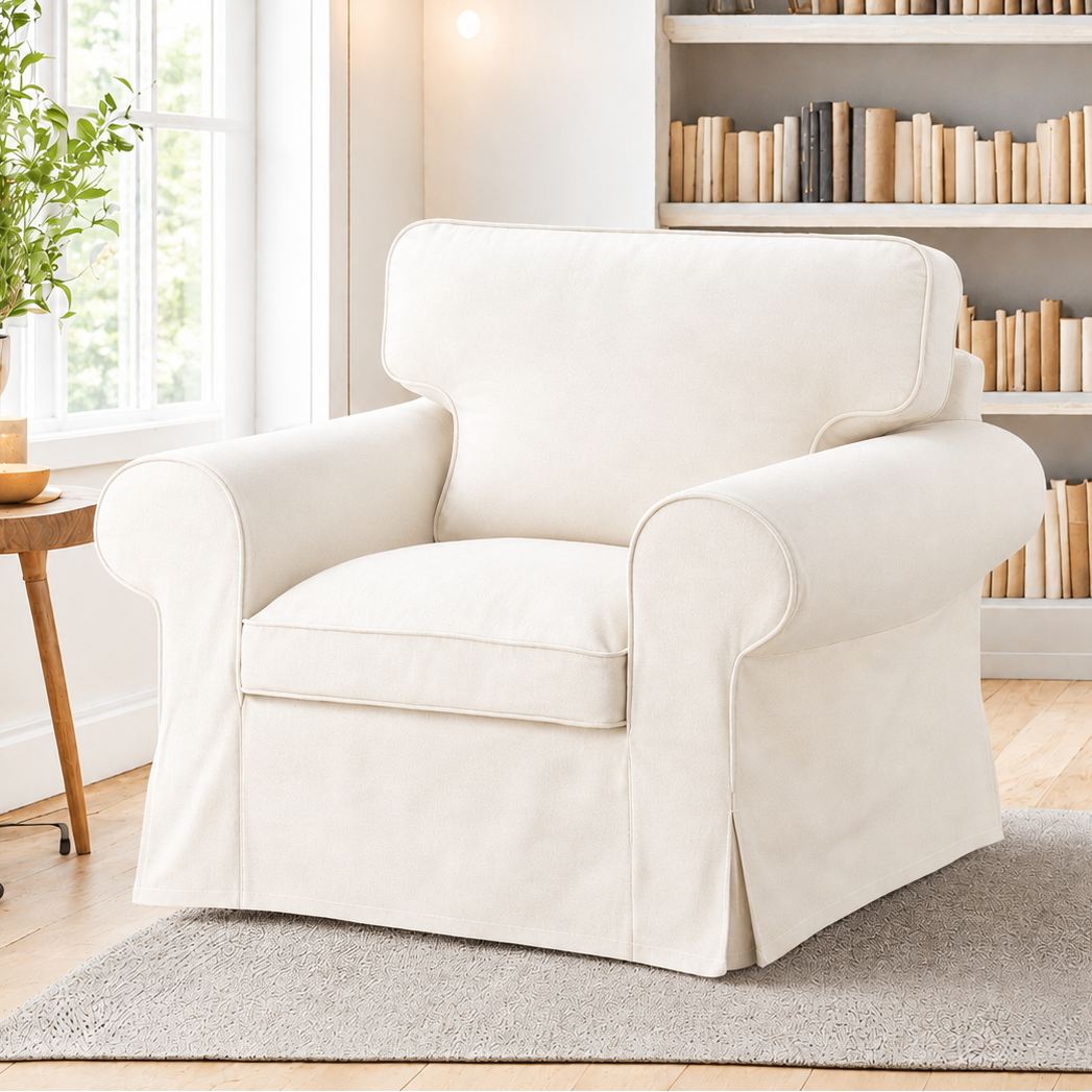 White armchair in a cozy living room with a bookshelf and window.