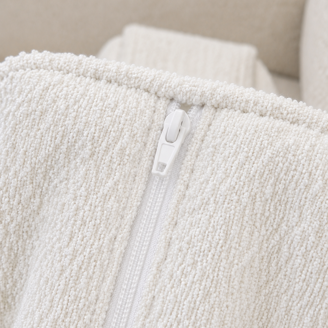 Close-up of a textured white fabric with a zipper detail on a neutral background